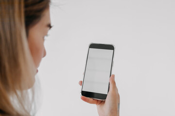 Close up of Asian Thai woman holding presenting smartphone and showing white blank screen phone, isolated on white background.