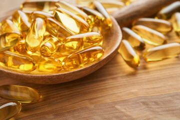 Close up capsules with Vitamin D, E or Omega 3,6,9 fatty acids in bottle on old wooden backgrounds. Food supplement oil filled fish oil. Natural supplements for healthy good life concept. Banner.