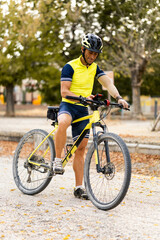 An adult man wearing sports clothing and a prosthetic arm is riding a mountain bike. The man is configuring his mobile phone to use the GPS navigator. Concept of disabled cyclists.