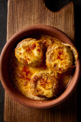 Close-up vertical top view of baked mushrooms stuffed with suluguni cheese, highlighting its rich textures and flavors, served on a Georgian 'keci' clay plate