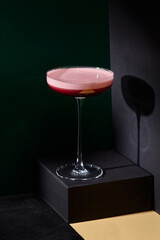 Berry sour cocktail elegantly presented against a black background with a distinct shadow from the glass, embodying a minimalist color block style