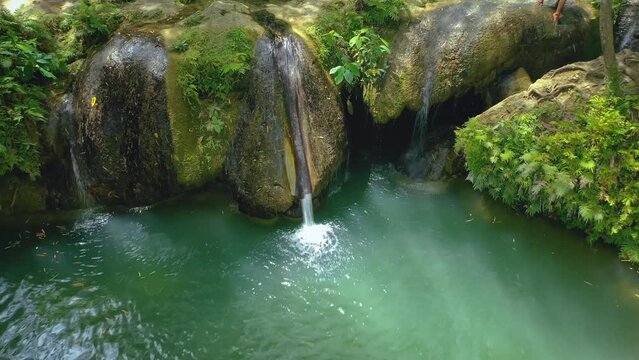 Cambugahay falls, Siquijor island, Philippines. Low altitude cinematic drone travelling. Filipino tourists swimming and playing in the turquoise lagoons. Famous travel destination.