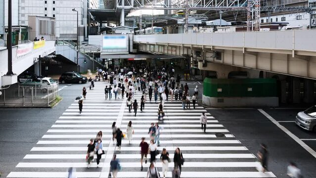 Timelapse of crowded Asian people walk cross road, car and train traffic transportation in downtown Osaka Japan. Japanese culture, urban lifestyle, Asia transport, commuter or city life concept