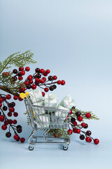 caddy filled with colorful gifts against a luminous sky-blue background and A branch of holly with its red berries