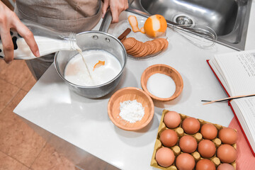 Pouring milk into the cauldron to make custard as seen from above