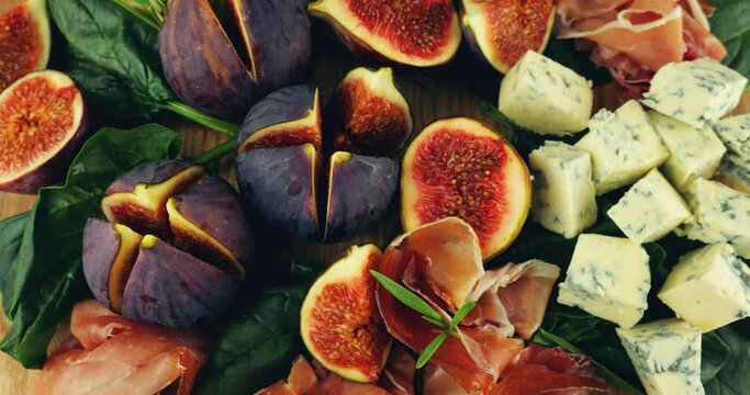 Figs, jamon, spinach leaves and blue cheeses on a wooden board. Snacks set.