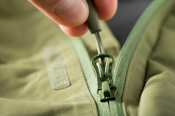 close-up zipper lock on green clothes.