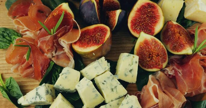 Figs, jamon, spinach leaves and blue cheeses on a wooden board.