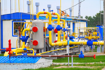 Fototapeta premium Gas distribution station. Industrial facility. Gas processing station with yellow pipes on a summer day in an open space. Gas supply. Transportation of natural gas through pipes. Background.