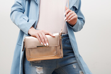 Beauty fashion. Glamorous girl in fashionable clothes, stylish look. Trendy woman in stylish blue coat and jeans with little golden bag clutch . Fashion accessories - obrazy, fototapety, plakaty