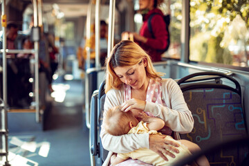 Young woman breastfeeding her baby on the bus