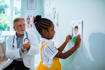 Little girl putting a drawing on the wall of a pediatrician office