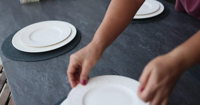 A waiter putting on the white plate on a table with a white table cloth. Plate on the table.