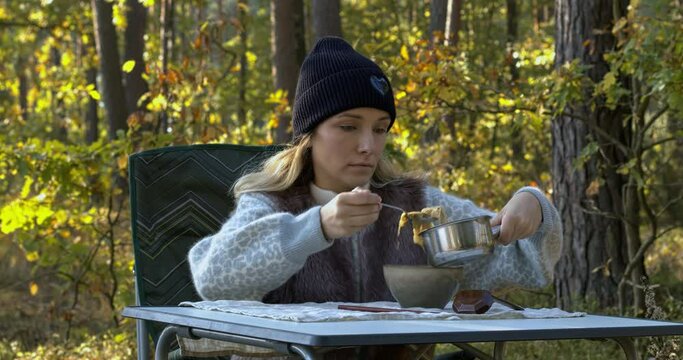 Woman pouring hot miso soup into a bowl. Outdoor meal in autumnal forest.