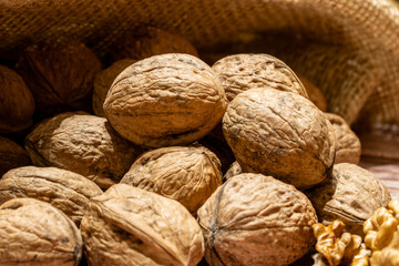 Closeup of whole walnuts coming out of a sack on a table