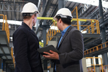 A couple of businessman work out at the sideline of an electric train garage