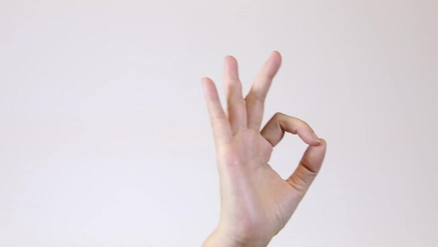 Crop female showing OK gesture. Static shot of anonymous woman gesturing okay with raised arm against vivid white background