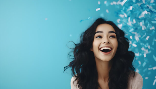 Beautiful Young Woman Shocked Surrounded by Confetti. Happy after hearing good news. Empty space for text. Blue background
