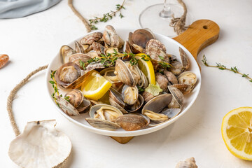Vongole shellfish appetizer served with lemon and herbs on a light background.