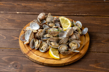 Board with prepared vongole with lemon and herbs,wooden table