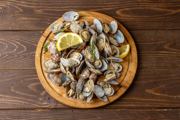 Vongole clams cooked served on a wooden board, wooden background. Cooked shellfish. View from above