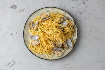 Spaghetti with shellfish, vongole herbs in a plate on a gray concrete background.. Pasta with seafood. top view.