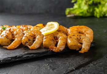 Grilled garlic shrimp with spices close-up,dark table.