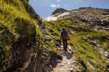 Fototapeta na wymiar A man with a backpack climbs a scenic rocky trail to a mountain peak, Austria