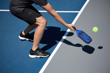 An athlete playing pickleball on a blue and gray court - obrazy, fototapety, plakaty