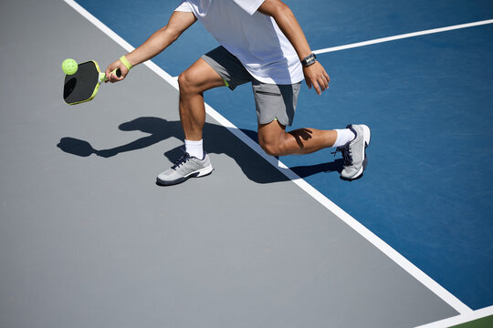 An athlete playing pickleball on a blue and gray court