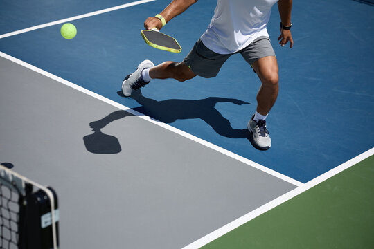 An athlete playing pickleball on a blue and gray court