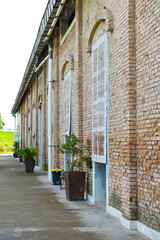 An old brick  historical building featuring charming wooden shutters and vibrant potted plants adorning the entrance.