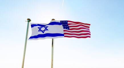 Fototapeta premium Israel and United states flags waving against a blue sky background. 