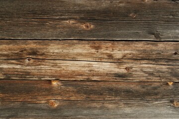 The cracked wooden wall of an old building. A fragment of a brown old wooden wall.