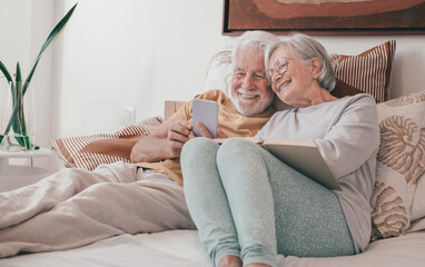 Video call concept. Portrait of happy senior couple together in bed, handsome people using phone webcam for video chat