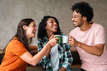 group of friends celebrating and toasting with coffee mugs in coffee shop