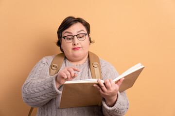 confident university student reading book to study in all beige colors. dedication, effort...