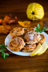 Cooked fried round pancakes with quince filling on a wooden table