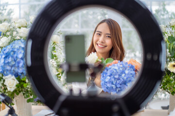 Young asian Florist woman recording video lesson on smartphone webcam giving professional course...
