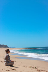 Young female practicing meditation in lotus yoga on the beach. Yoga woman. Morning Meditation. Young female traveler. Solo Traveling. Happy.