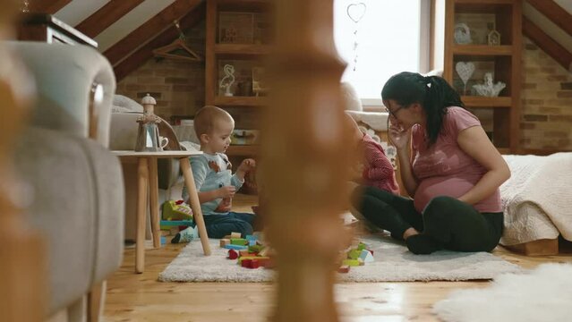 Family with two children playing with wooden blocks on the floor at home.