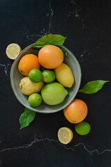 White ceramic bowl filled with a selection of yellow and green citrus fruits - limes and lemons