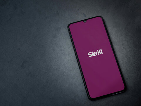 Lod, Israel - July 16,2023: Skrill app launch screen on smartphone on dark marble stone background. Top view flat lay with copy space.