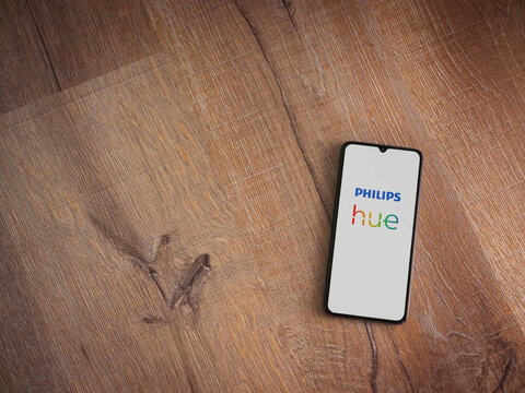 Lod, Israel - July 16,2023: Philips Hue app launch screen on smartphone on wooden background. Top view flat lay with copy space.