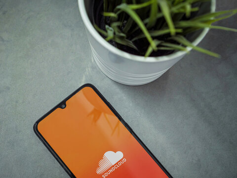 Lod, Israel - July 16,2023: Modern workspace with smartphone with SoundCloud app launch screen on marble background. Close up top view flat lay.