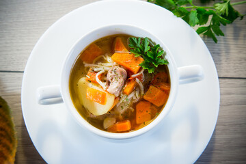 Autumn soup with chicken, noodles and autumn vegetables in a bowl .