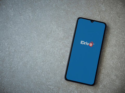 Lod, Israel - July 16,2023: IDrive Online Backup app launch screen on smartphone on ceramic stone background. Top view flat lay with copy space.