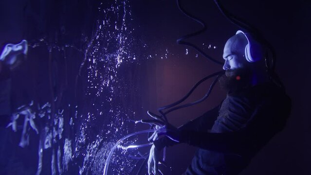 A young brutal man in a futuristic suit and headphones listens to music underwater.