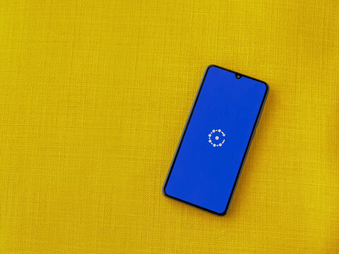 Lod, Israel - July 16,2023: Fing app launch screen on smartphone on yellow fabric background. Top view flat lay with copy space.