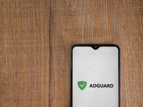 Lod, Israel - July 16,2023: AdGuard app launch screen on smartphone on wooden background. Top view flat lay with copy space.